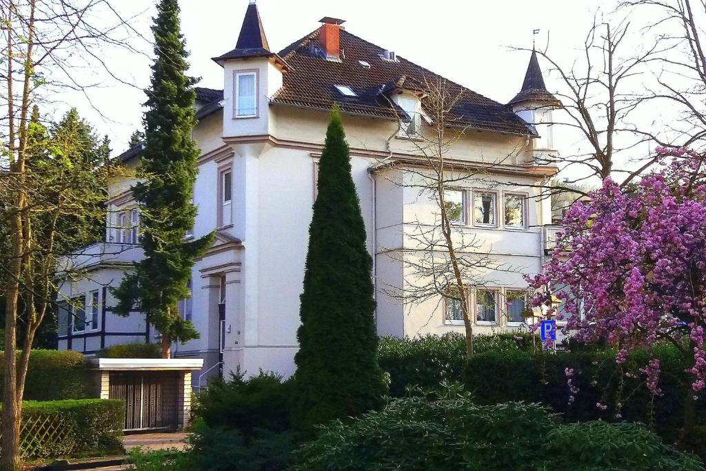 ein weißes Haus mit Bäumen davor in der Unterkunft FeWo Radau in Bad Harzburg