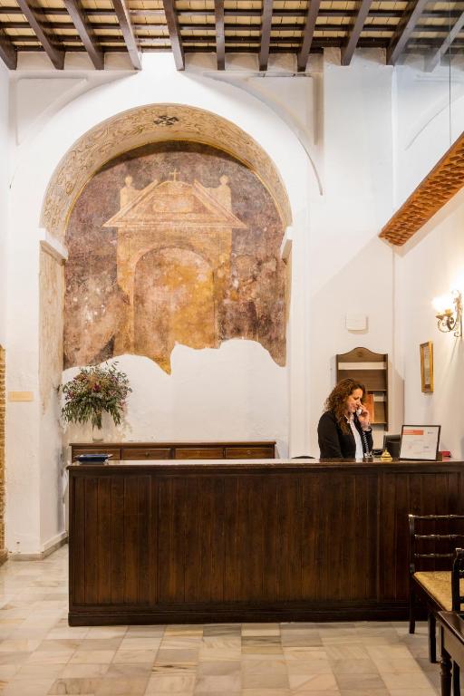 a woman talking on a cell phone at a counter at Hotel Tugasa Convento San Francisco in Vejer de la Frontera