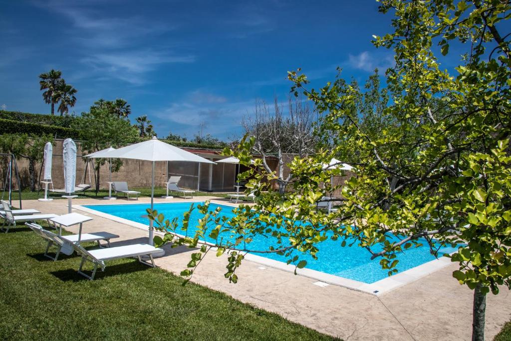 uma piscina com espreguiçadeiras e um guarda-sol em Corte dei Melograni Hotel Resort em Otranto