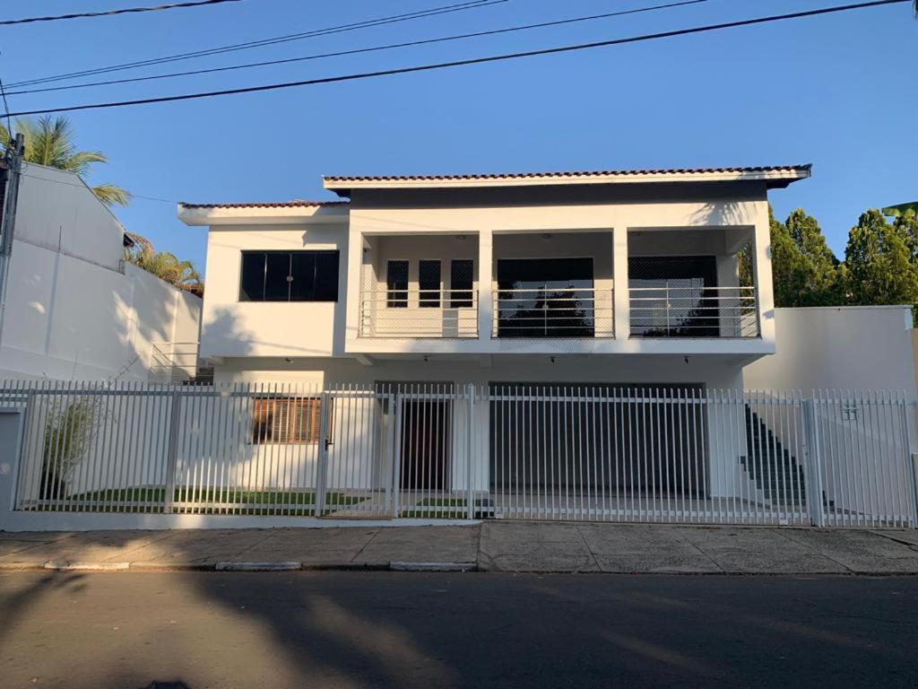 a white house behind a white fence at Casa espaçosa para lazer em família in Águas de São Pedro