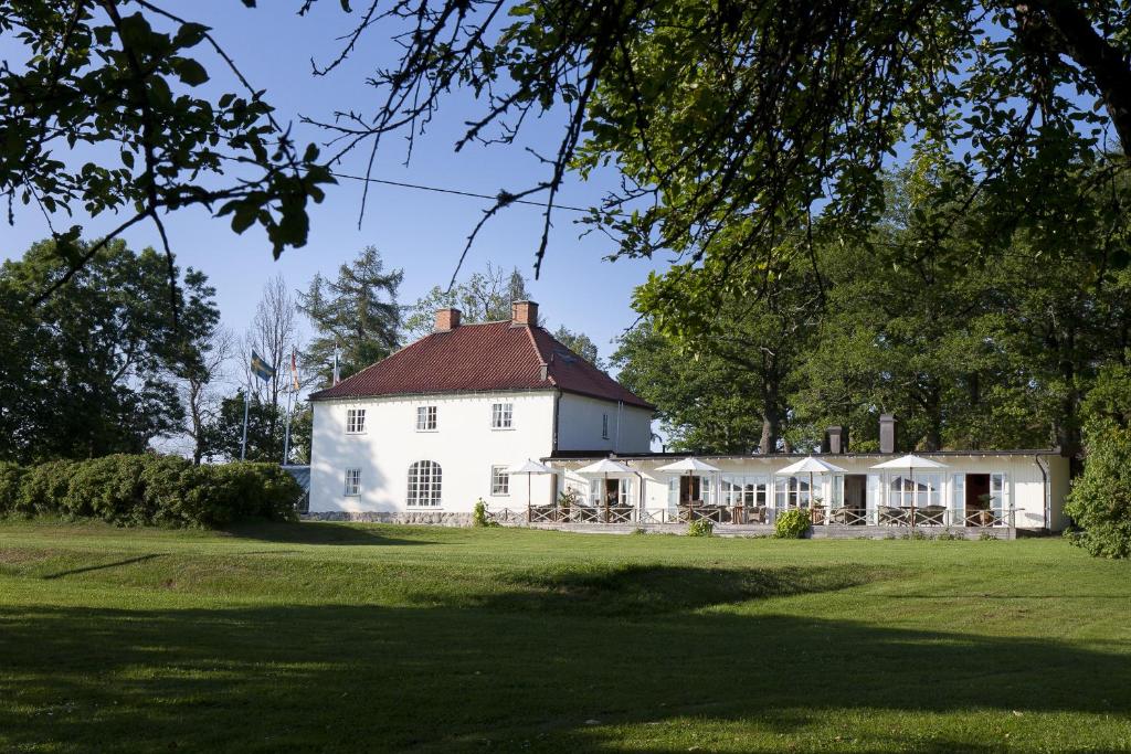 una casa blanca con techo rojo en un campo verde en Stegeborg Trädgårdshotell en Stegeborg