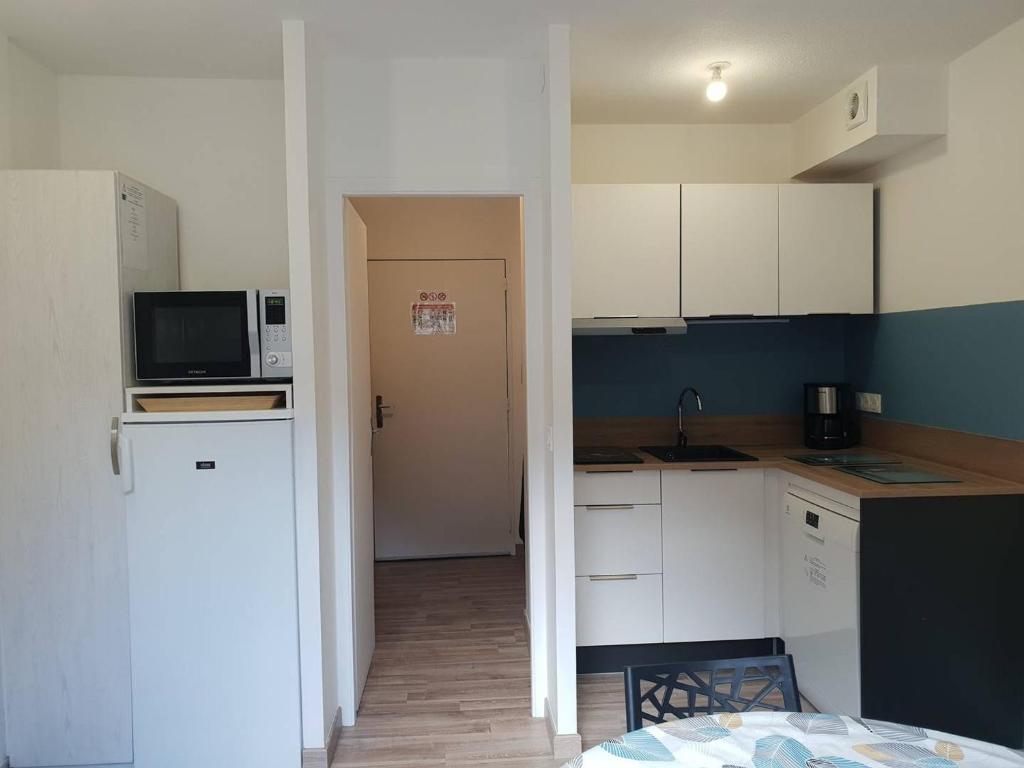 une petite cuisine avec des armoires blanches et un micro-ondes dans l'établissement Appartement T2bis proche centre, 4-6 pers, parking - FR-1-234-297, à Cauterets
