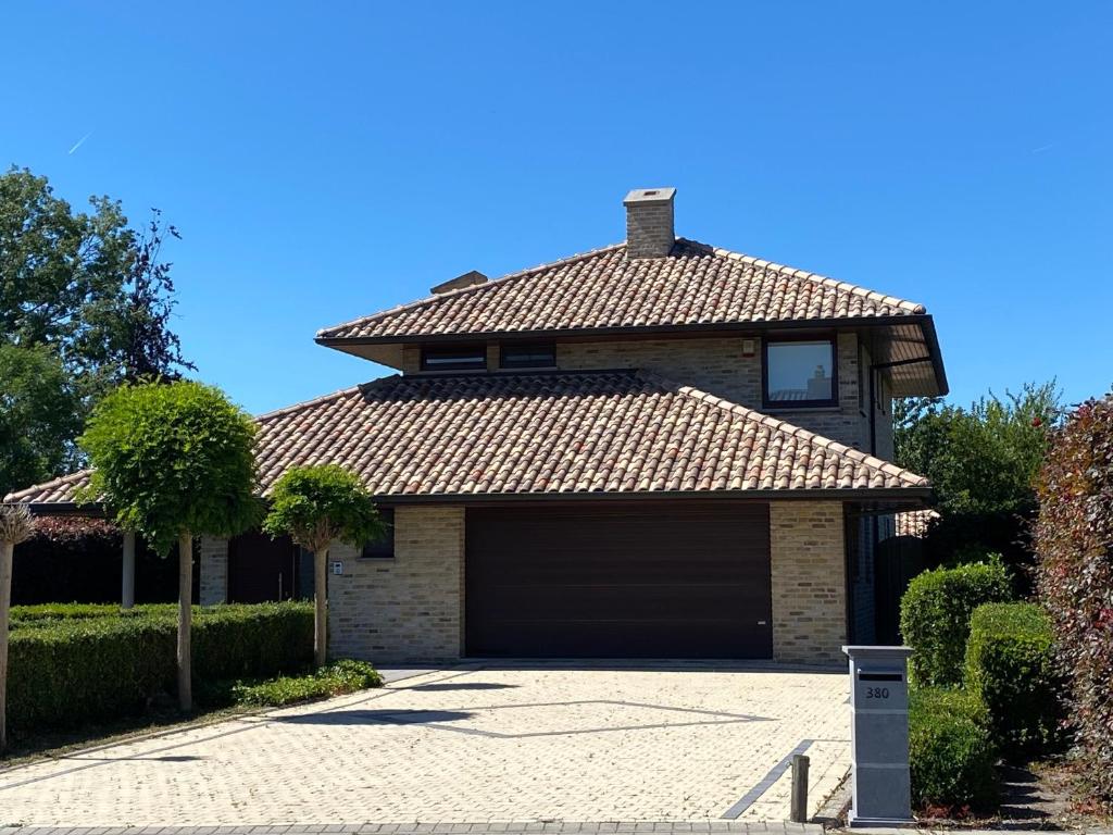 a house with a garage in a driveway at Modern Spanish Hacienda - 10km from the coast in Ichtegem