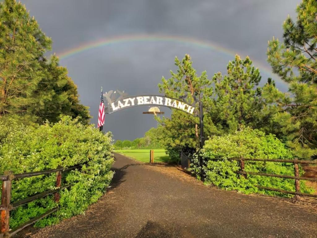 a rainbow in the sky over a driveway with a lay dean farm sign at Lazy Bear Ranch in Weiser