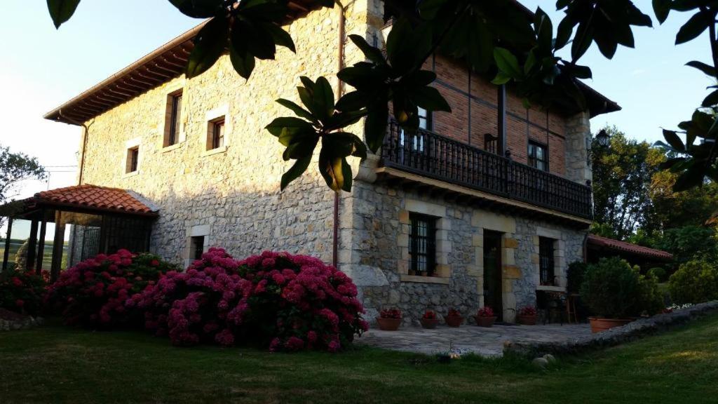 un gran edificio de piedra con flores delante en Posada San Tirso, en Toñanes