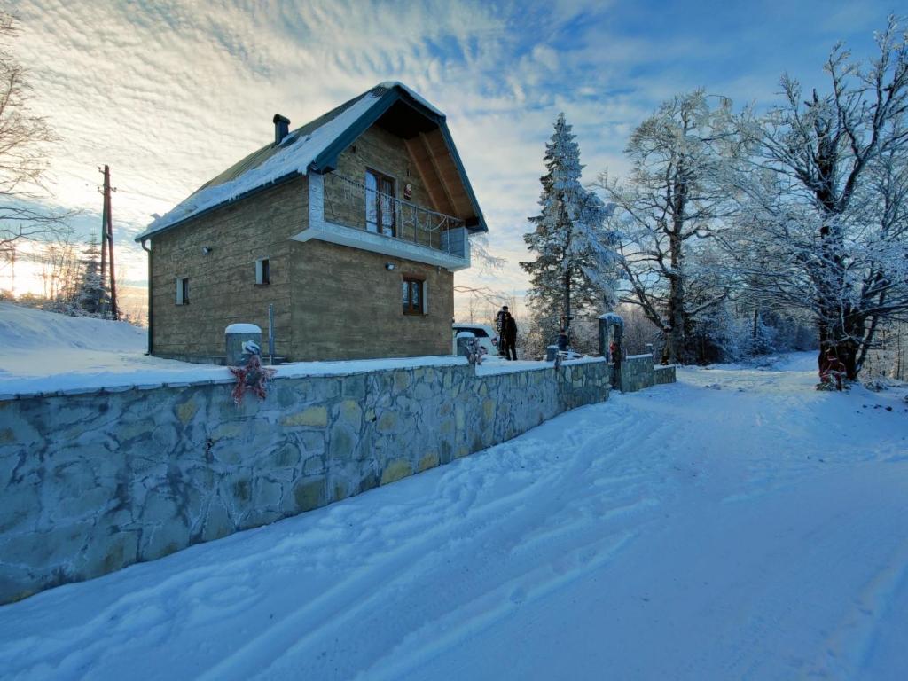 a building in the snow with a wall at Konak Mara- Komovi in Andrijevica