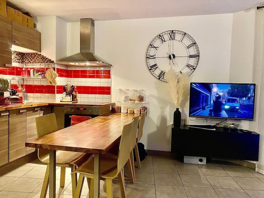 a kitchen with a table and a large clock on the wall at Joli T2 dans Annecy in Annecy