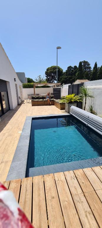 - une piscine au-dessus d'une maison avec une terrasse en bois dans l'établissement Charmante villa proche de la plage (classée 3*), à Pérols