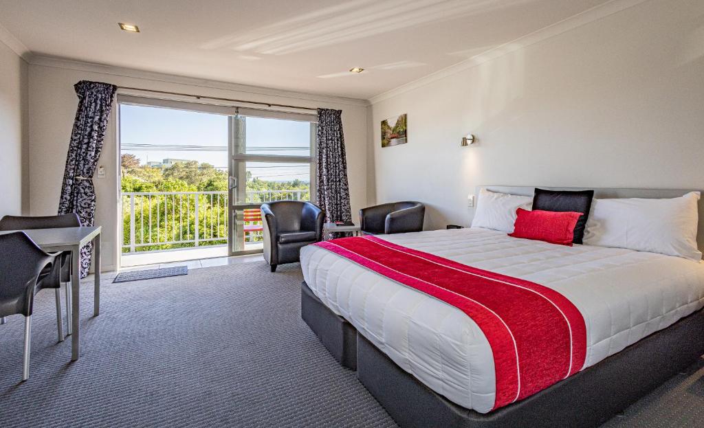 Habitación de hotel con cama y ventana grande en Pukekura Motor Lodge, en New Plymouth