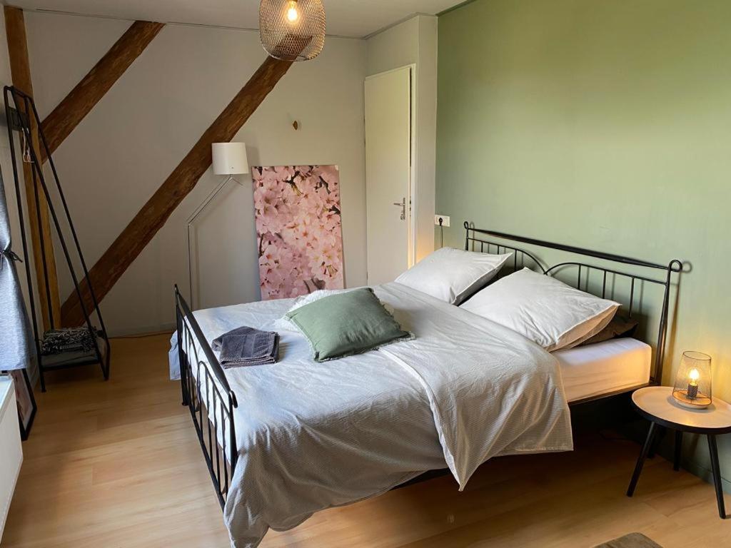 um quarto com uma cama e uma mesa com um candeeiro em Bed en Breakfast In het Fruit em Zuidoostbeemster