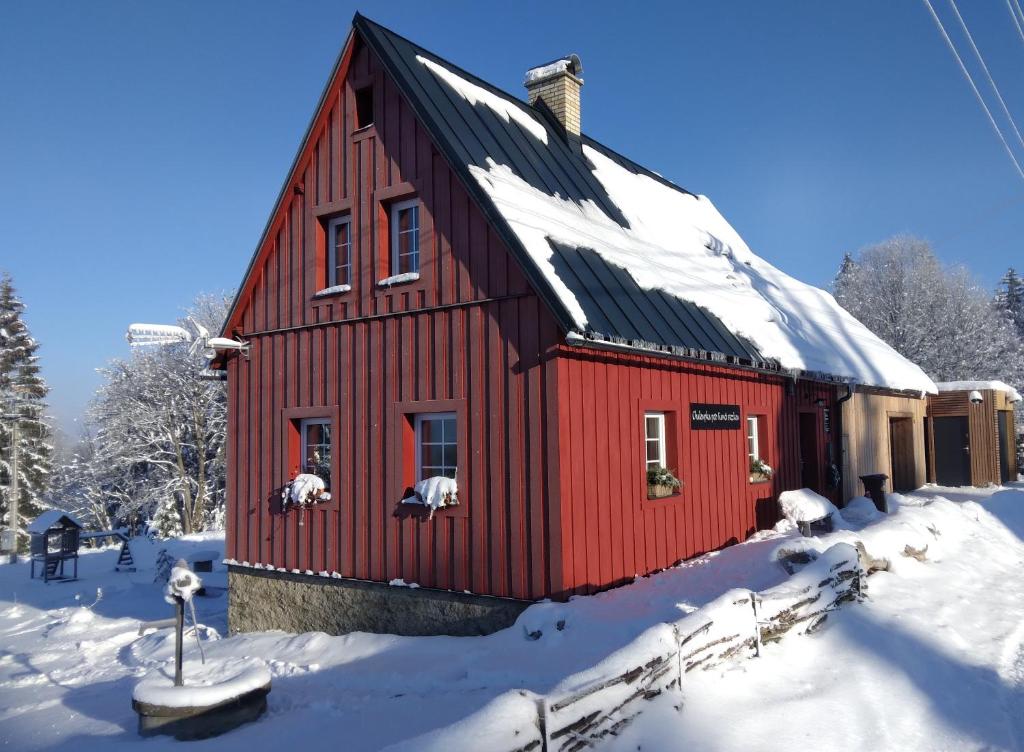 uma casa vermelha com neve no telhado em Chaloupka pod Kančí stezkou em Nova Ves nad Nisou