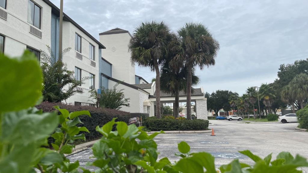 a building with palm trees in front of a street at Destiny Palms Hotel Maingate West in Kissimmee