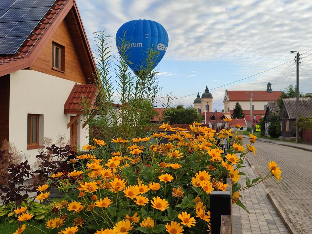 a blue balloon flying over a field of yellow flowers at Przystanek Tykocin - domki gościnne w sercu Podlasia in Tykocin