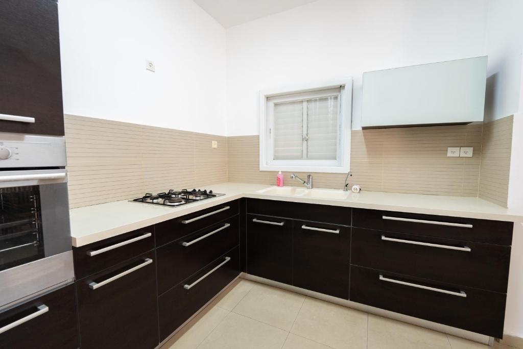 eine Küche mit schwarzen Schränken und einem Waschbecken in der Unterkunft Luxury & Big Families Apartment (7 Min f TLV) in Bat Yam