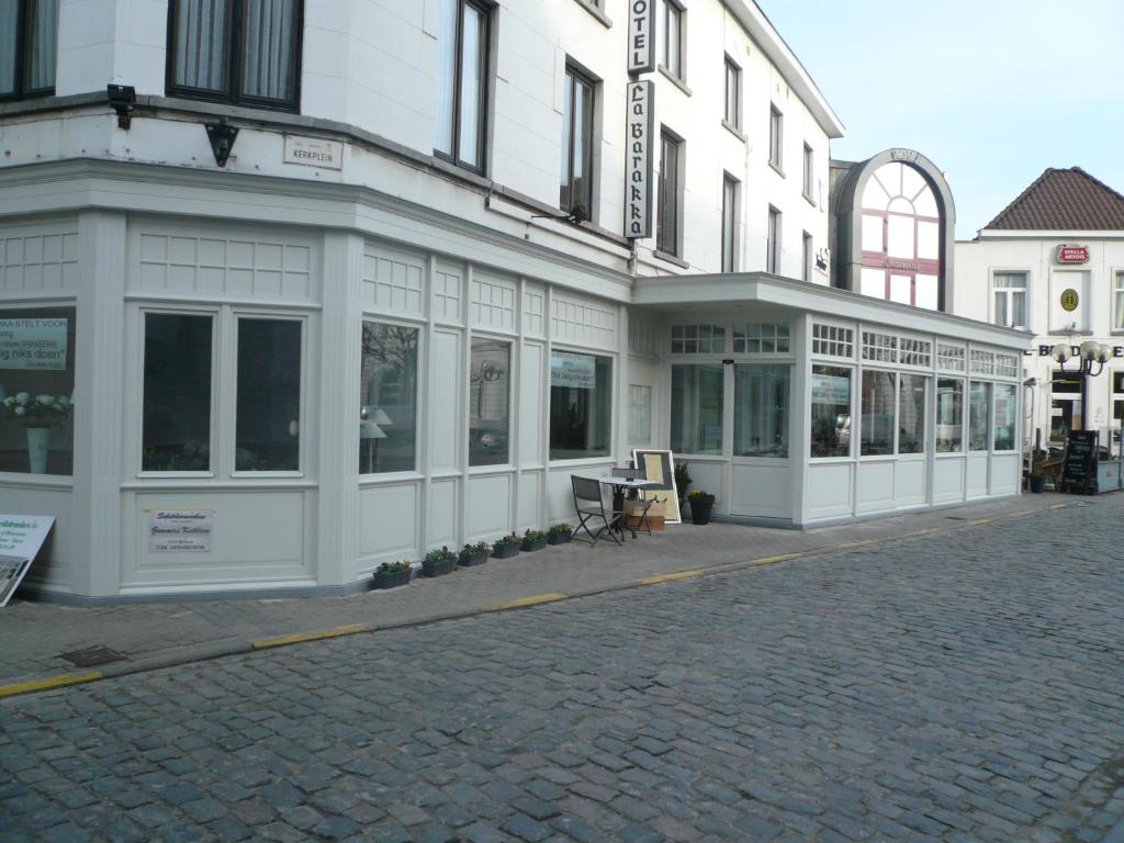 a white building on a street next to a building at Hotel La Barakka in Lokeren