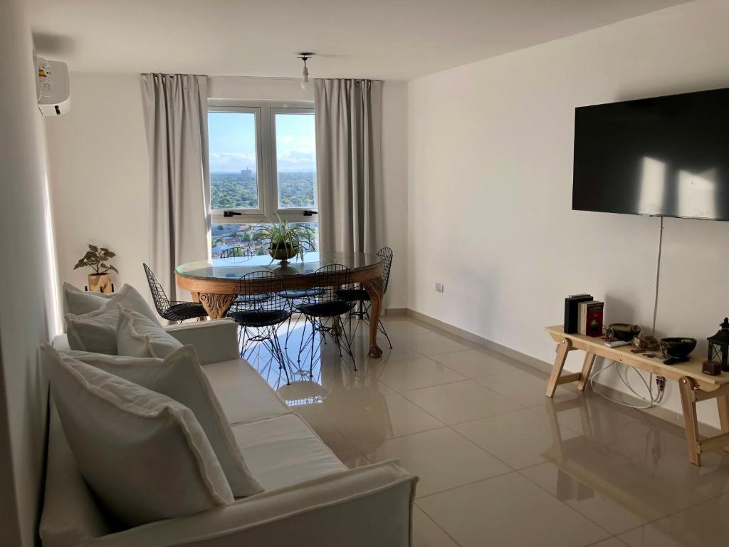 sala de estar con TV y mesa con sillas en Güemes Premium, 2 dorm con Vista a las Sierras ALOHA #2 en Córdoba