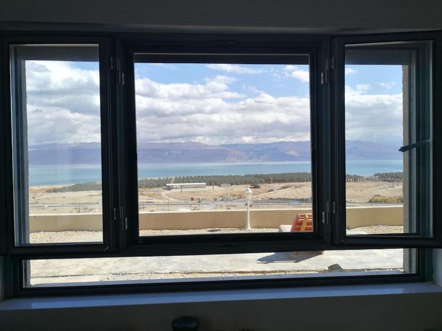 a window with a view of a beach and the ocean at Charming unit in Dead Sea in Ovnat