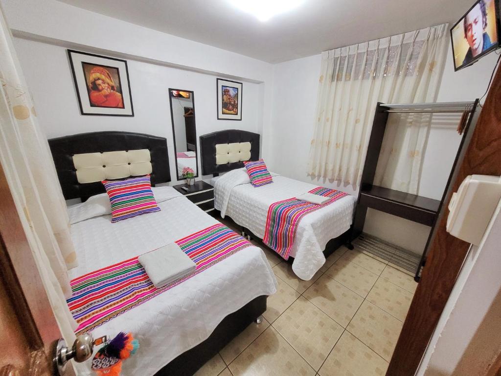 Hostal EL VIAJERO en Ollantaytambo في أولانتايتامبو: غرفة نوم بسريرين ومرآة
