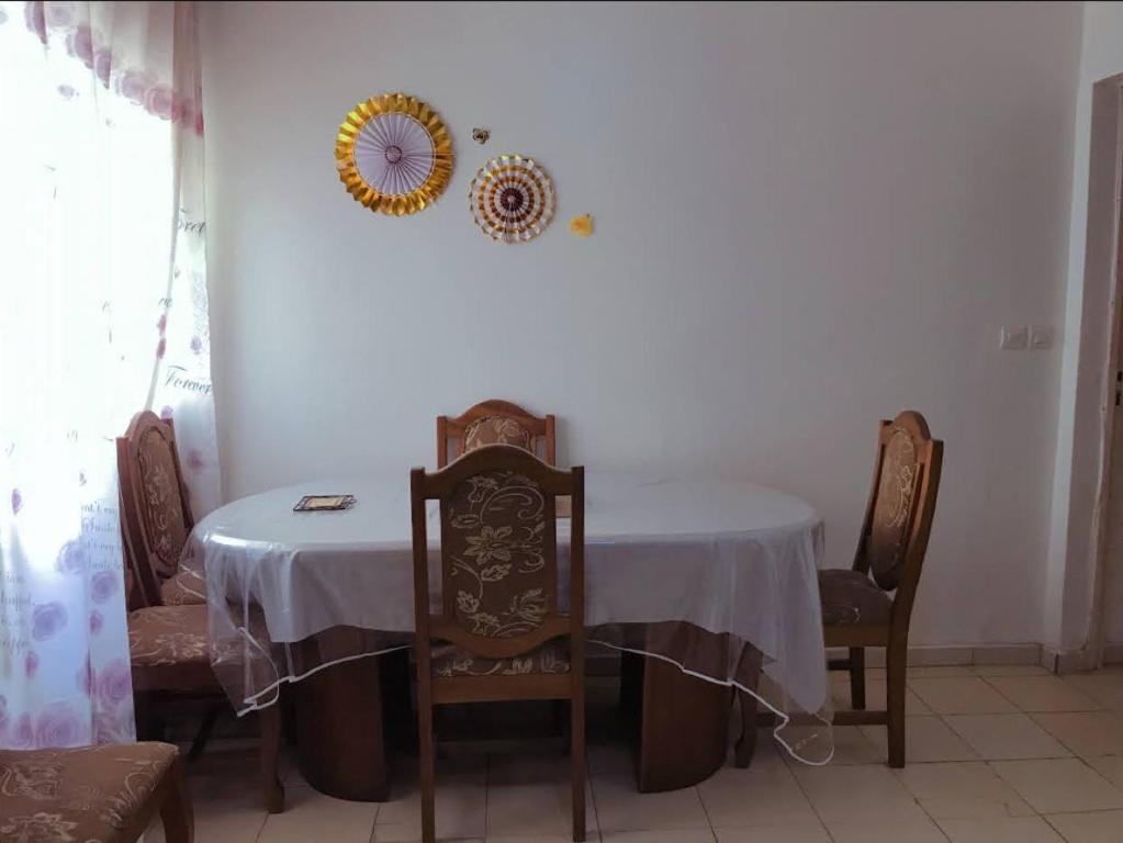 a dining room table with a white table cloth and chairs at Chambre in Dakar