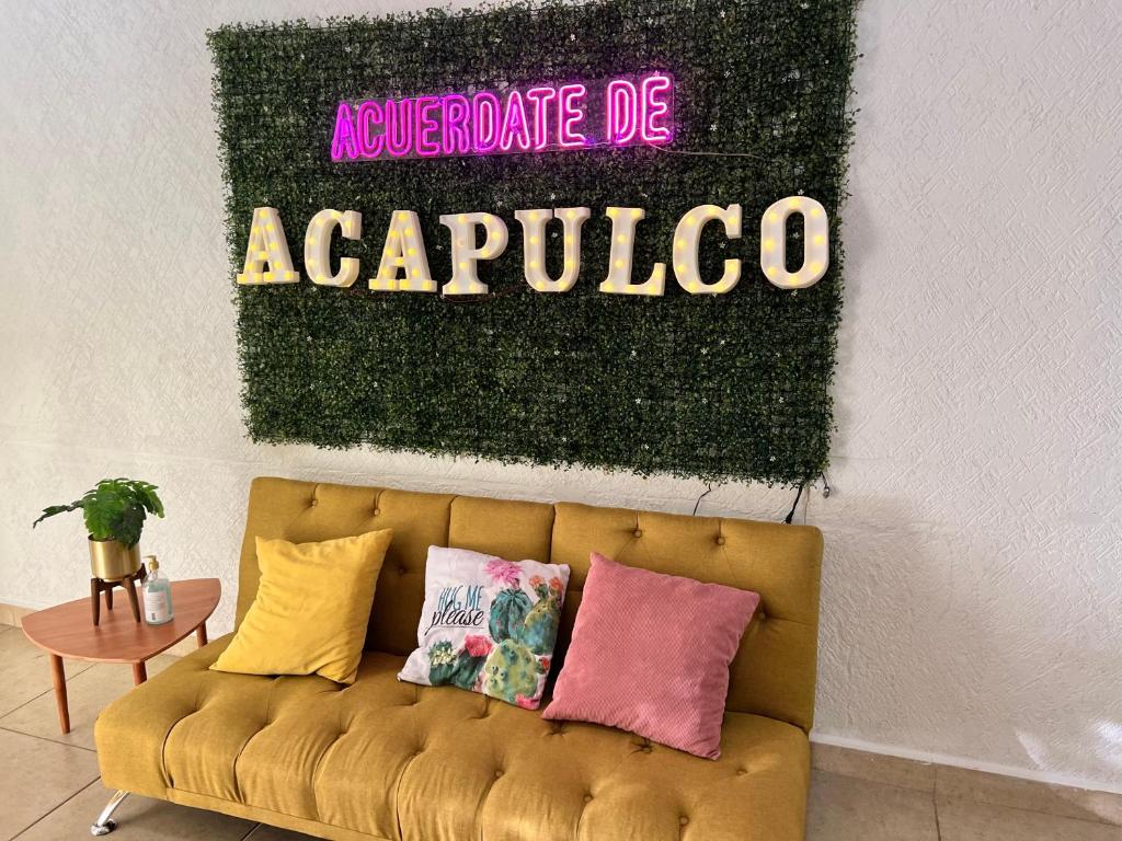un sofá amarillo en una habitación con un cartel en la pared en Departamento planta baja en Acapulco Diamante, en Acapulco