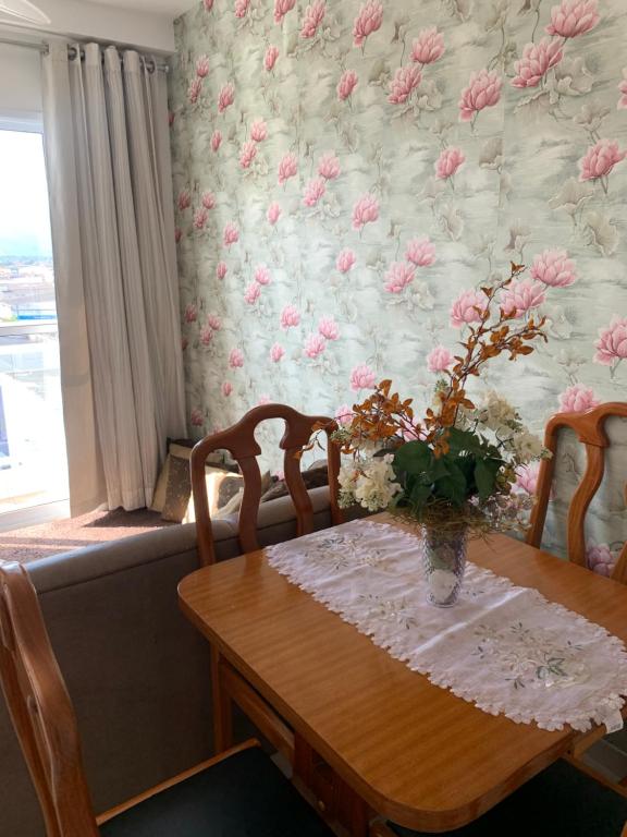 a dining room table with a vase of flowers at Espaço Mahina - Unidade Dez - Apartamento para temporada Praia Grande Ocian in Praia Grande