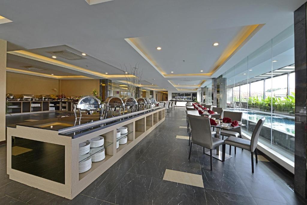 un ristorante con bar con sedie e tavoli di Serela Waringin by KAGUM Hotels a Bandung