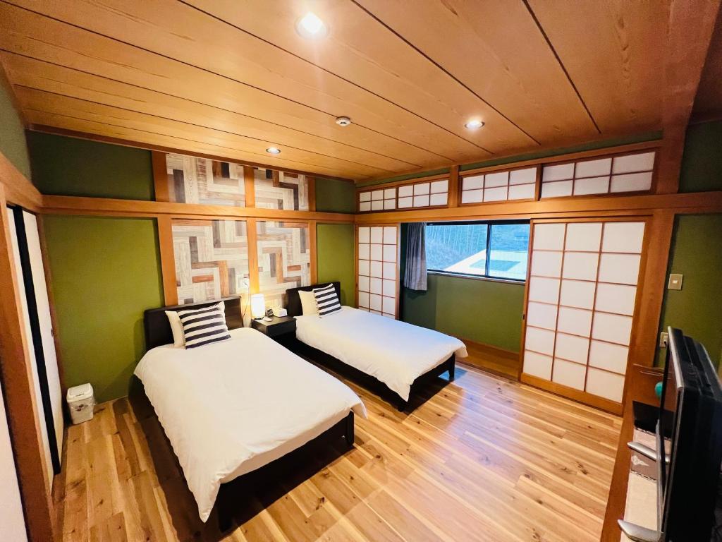 NARA japanese garden villa في نارا: سريرين في غرفة بجدران خضراء ونوافذ