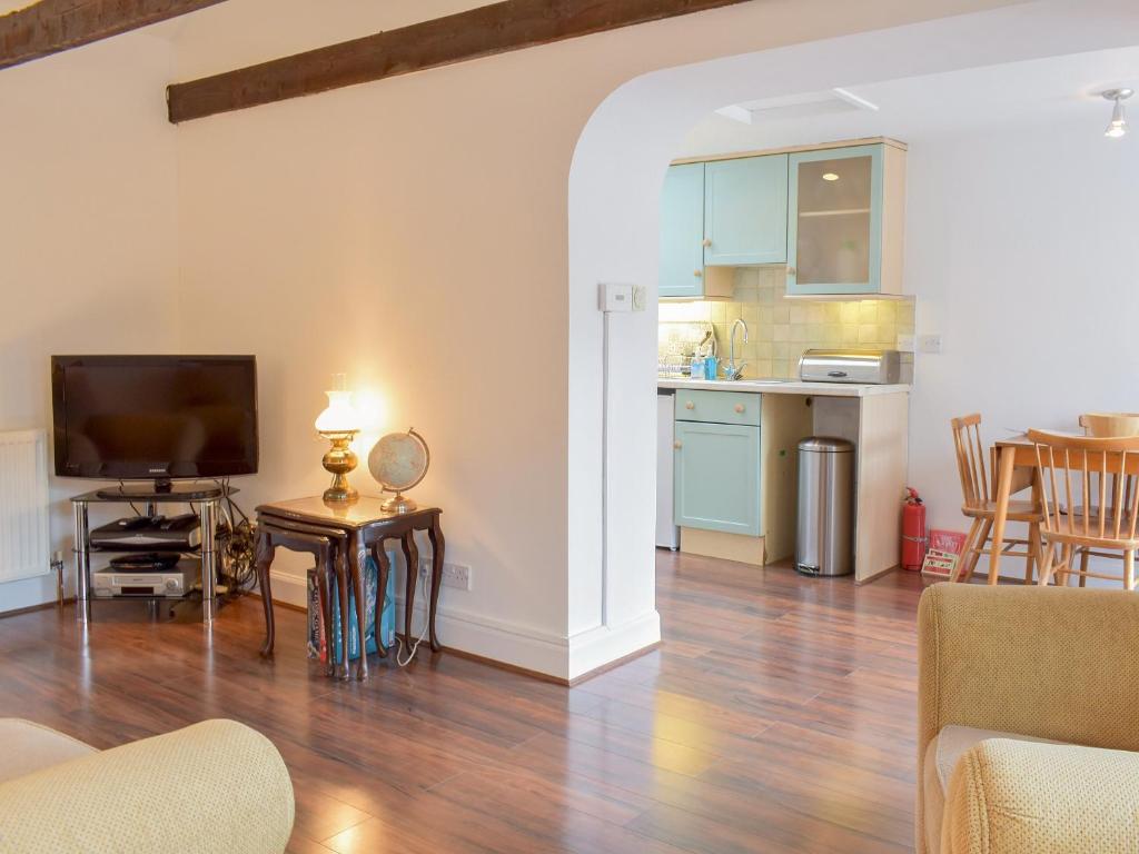 a living room with a television and a kitchen at The Bothy in Walkerburn