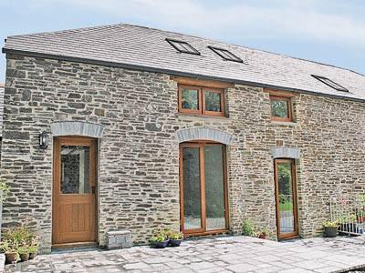 a brick house with a wooden door and windows at The Stable in North Petherwin