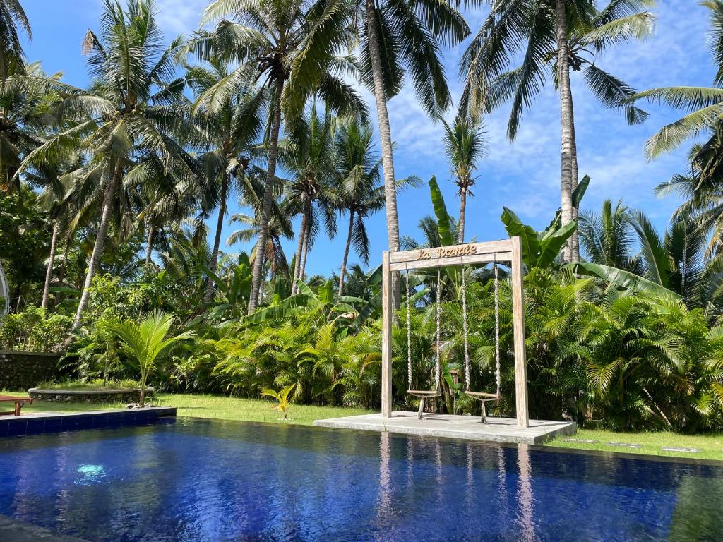a resort with a swimming pool and palm trees at La Royale Nusa Penida in Toyapakeh