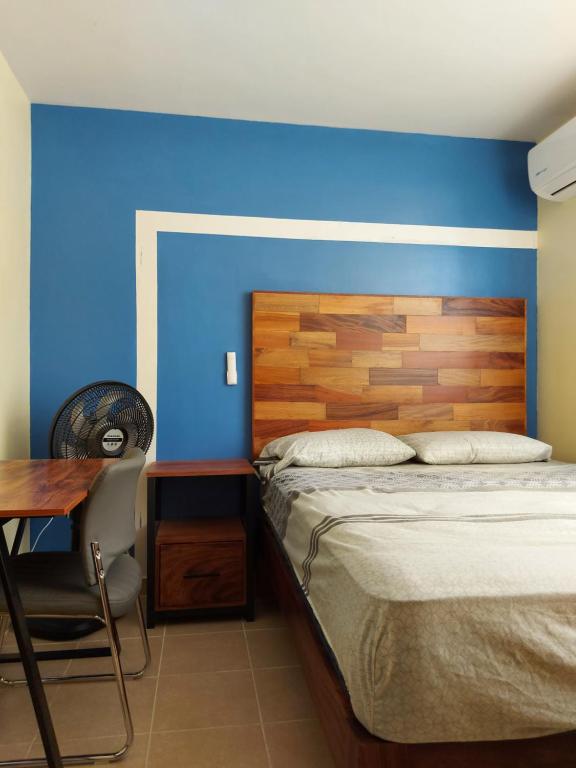 1 dormitorio con cama y pared azul en Xhunco House en Santa Cruz - Huatulco