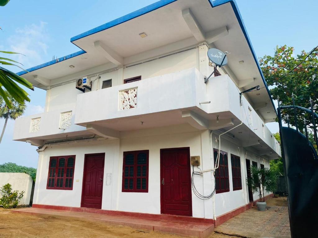 een wit gebouw met rode deuren en een straatlicht bij Sayura Guest House in Trincomalee