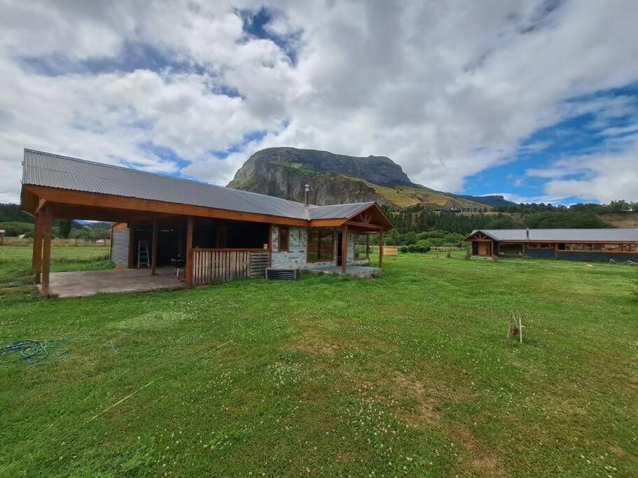 un bâtiment dans un champ avec une montagne en arrière-plan dans l'établissement Cabaña entre cerros y ríos, à Coyhaique