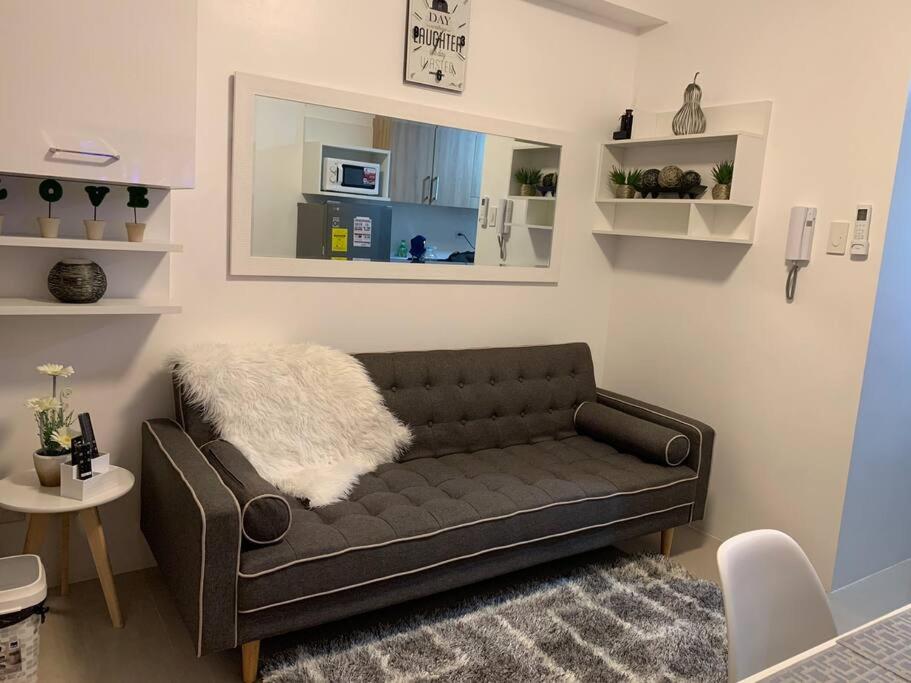 una sala de estar con un sofá marrón en una habitación en Katei elegantly designed 1-bedroom facing amenity, en Manila