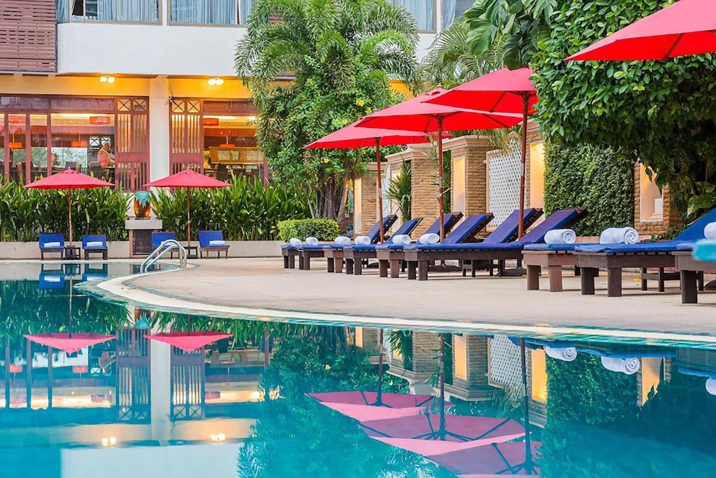 パタヤ・サウスにあるMountain Beach Resortのホテル内のスイミングプール(椅子、赤いパラソル付)