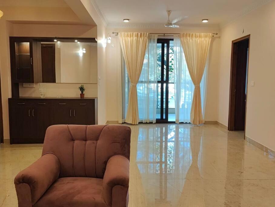 uma sala de estar com um sofá castanho e cortinas em Tara Suites Premium rooms in Central Indiranagar em Bangalore