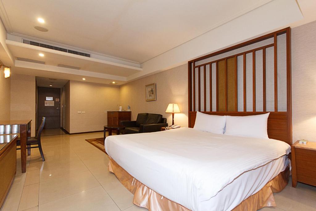 a hotel room with a large white bed and a chair at SLV Hotel Group-SLV Business Hotel in Zhonghe