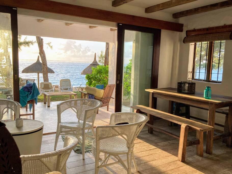 a porch with chairs and tables and a view of the ocean at BlueMoon Studio on the Beach! in Trou dʼ Eau Douce