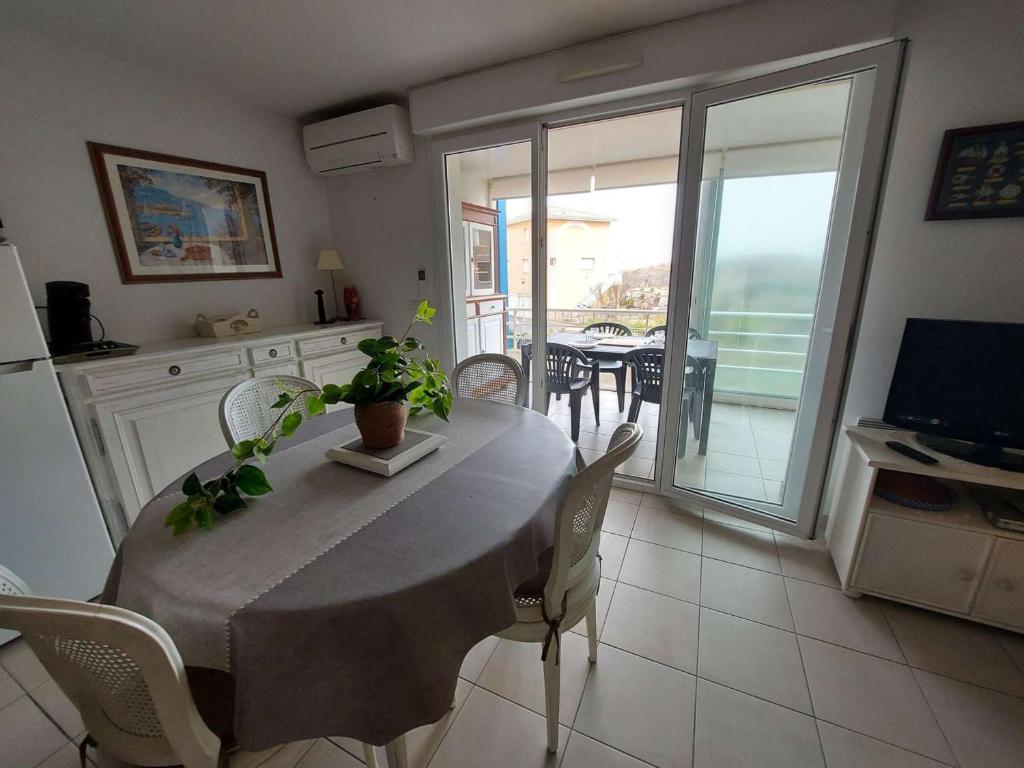une cuisine et une salle à manger avec une table et des chaises dans l'établissement Appartement climatisé 2P cabine, 50m de la plage, parking, loggia, équipements modernes - FR-1-326-747, à Marseillan