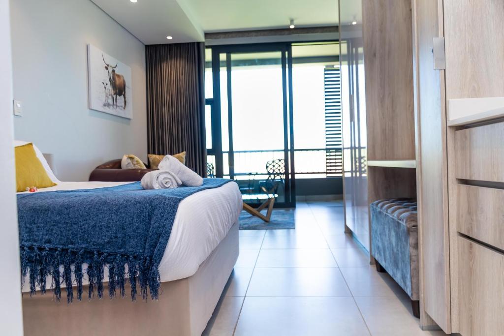 a hotel room with a bed with a blue blanket at Zimbali Lakes Boulevard Suites in Ballito