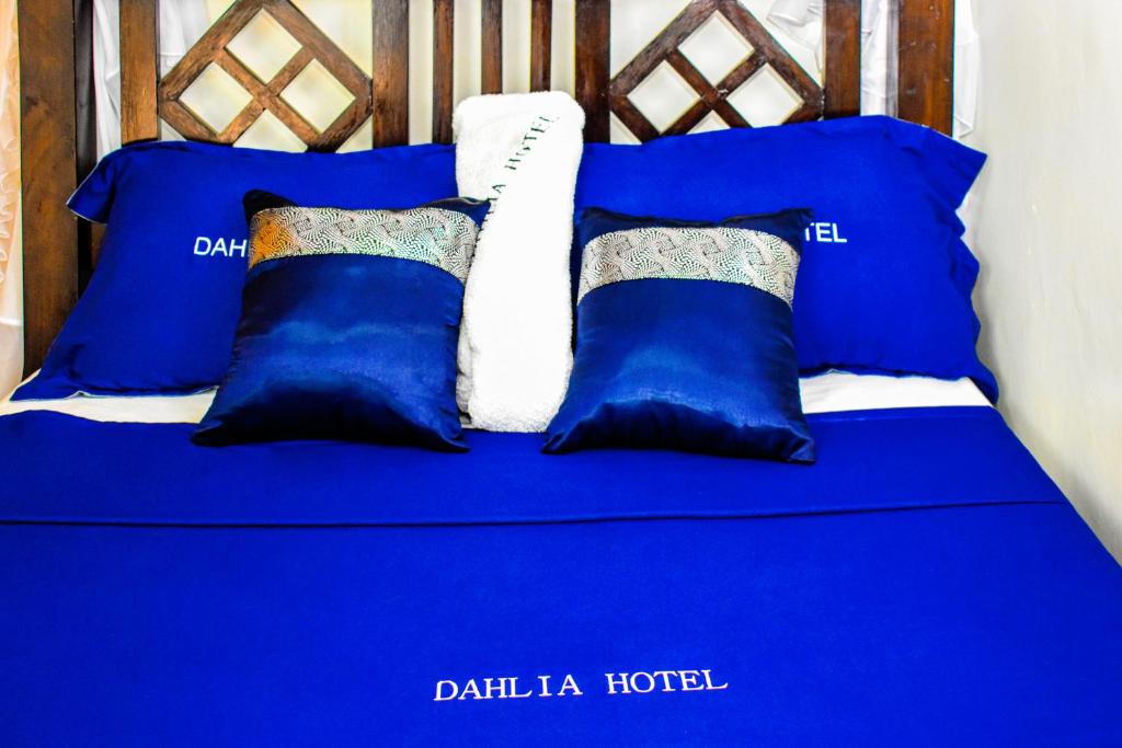 a bed with blue and white pillows on it at Dahlia Hotel and Accommodation in Homa Bay