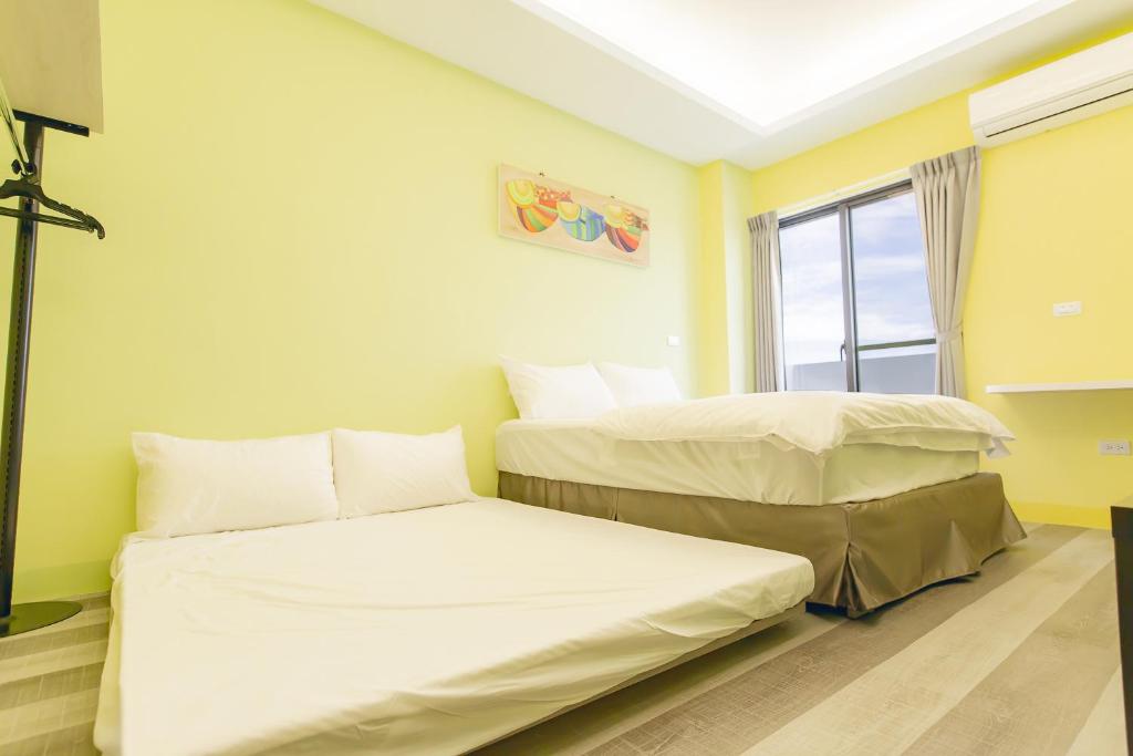 two beds in a room with yellow walls at Atami Penghuwan in Magong