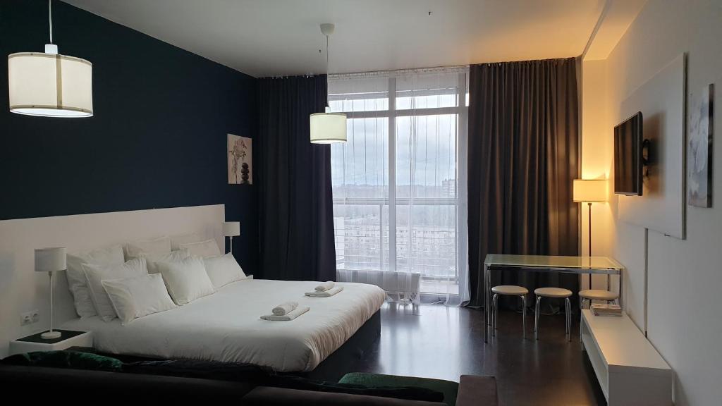 sypialnia z białym łóżkiem i dużym oknem w obiekcie Metropolia Apartments w Rydze