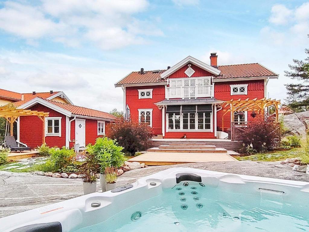 uma grande casa vermelha com uma banheira de hidromassagem em frente em 8 person holiday home in VAXHOLM em Rindö