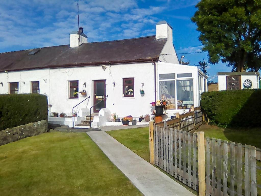una casa blanca con una valla delante en Ty Newydd Green Cottage, en Llanfachraeth