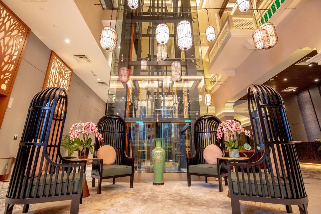A dramatic hotel seating area with high-backed chairs, orchids, and a glass elevator.
