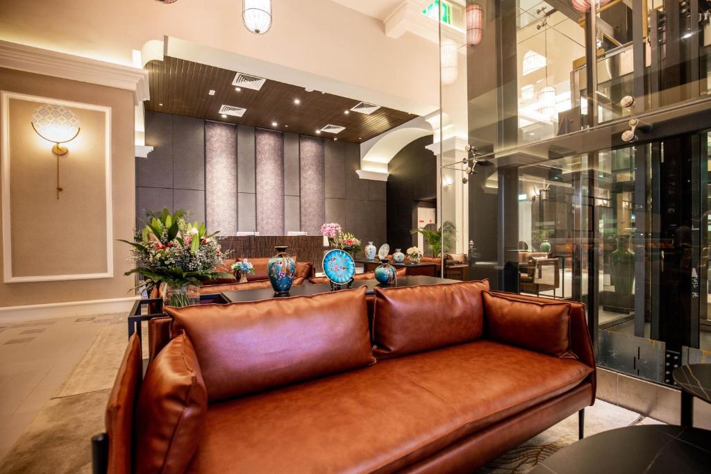 A leather sofa sits in an ornate hotel lobby beside the reception area.