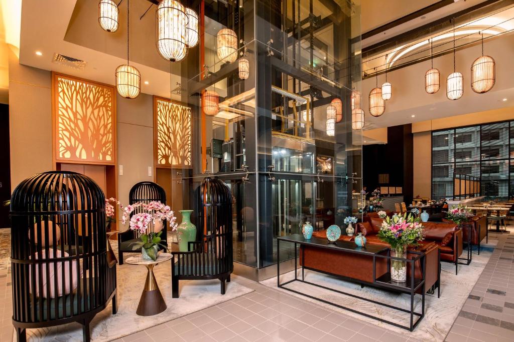 A decorated lobby lounge combines cage-style chairs, floral displays, and a glass elevator.