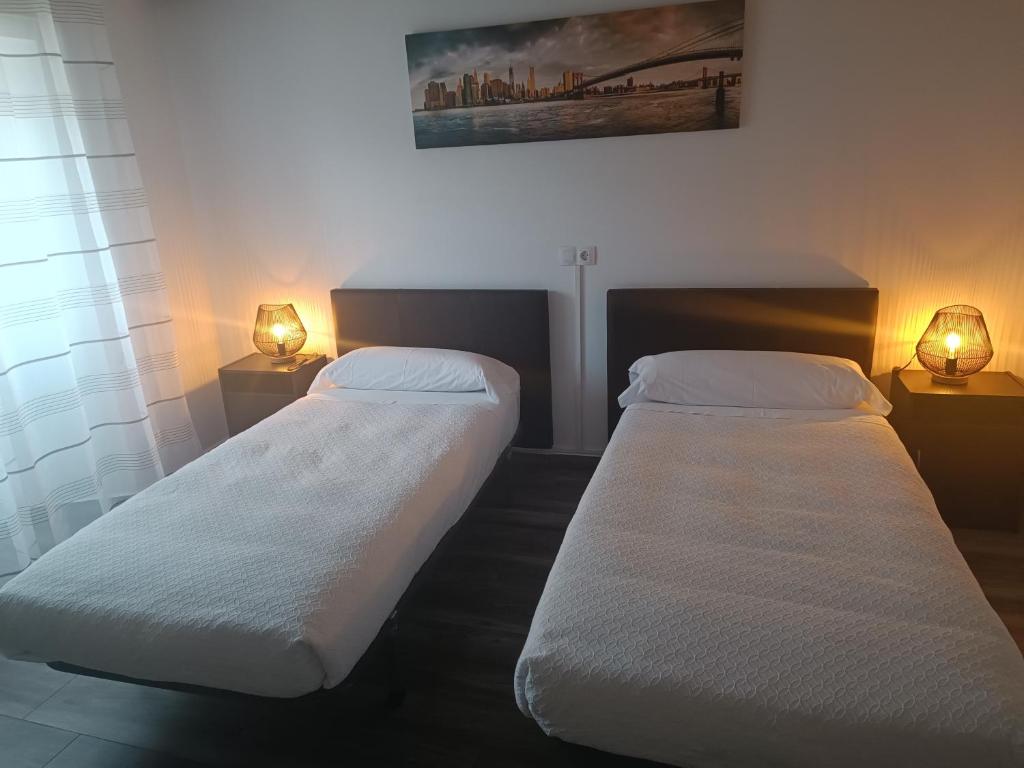 2 camas en una habitación con 2 lámparas en la pared en Hotel Rural Quintanapalla, en Quintanapalla