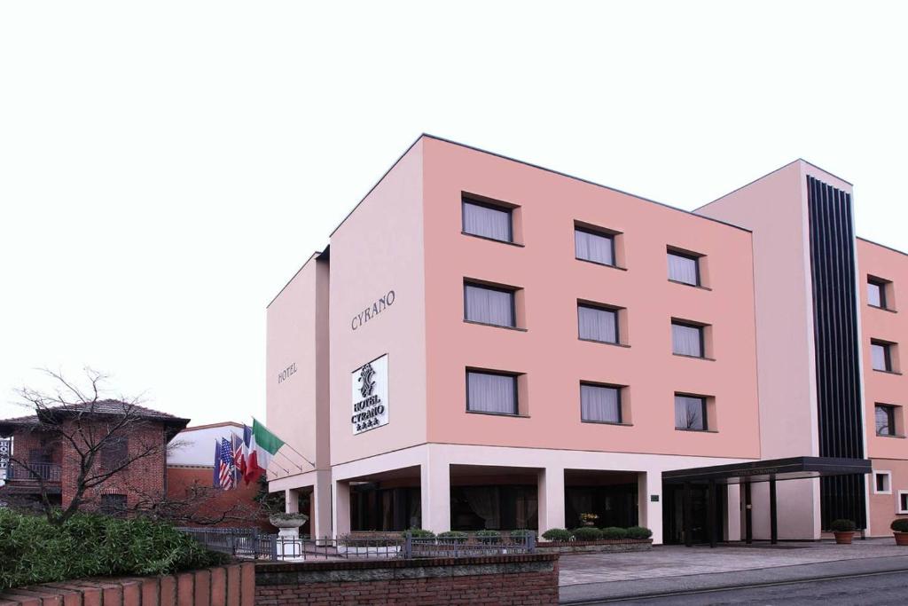 un bâtiment rose avec un panneau sur lui dans l'établissement Hotel Cyrano, à Saronno